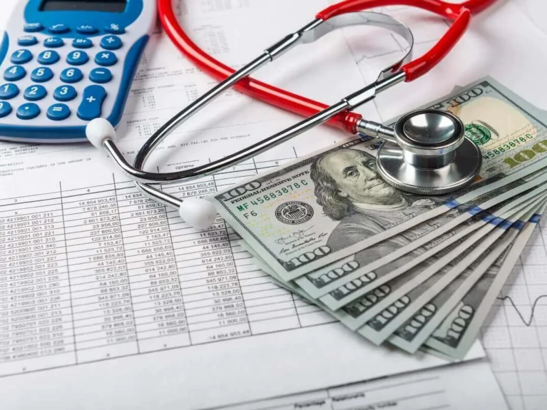 Stethoscope with calculator and stack of $100 bills