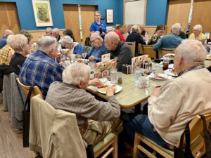 Many people sitting around tables enjoying brunch during a meeting
