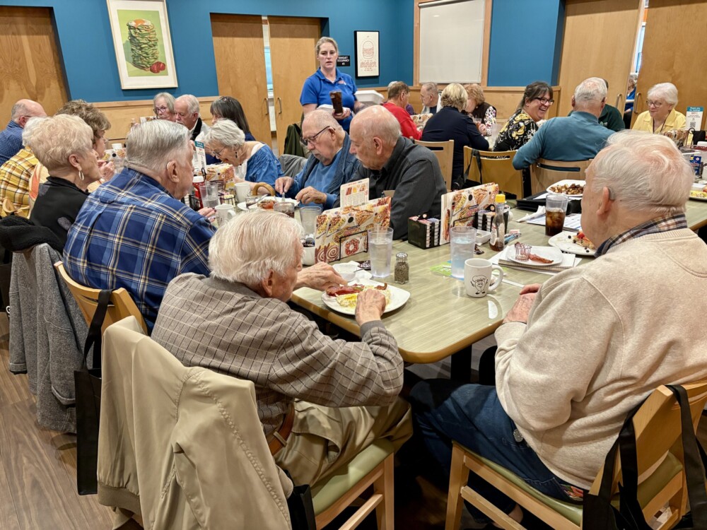 Many people sitting around tables enjoying brunch during a meeting