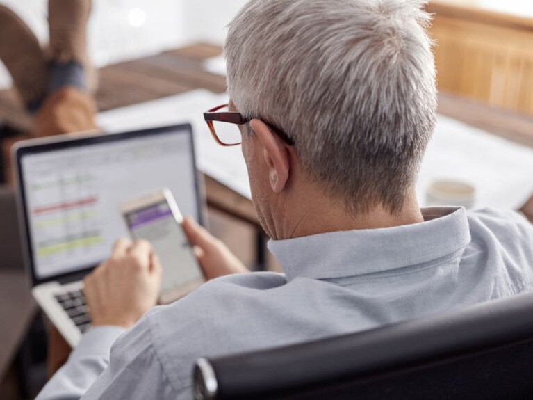 Man looking at laptop and mobile phone