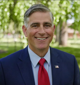 Portrait of man with red tie and blue jacket.