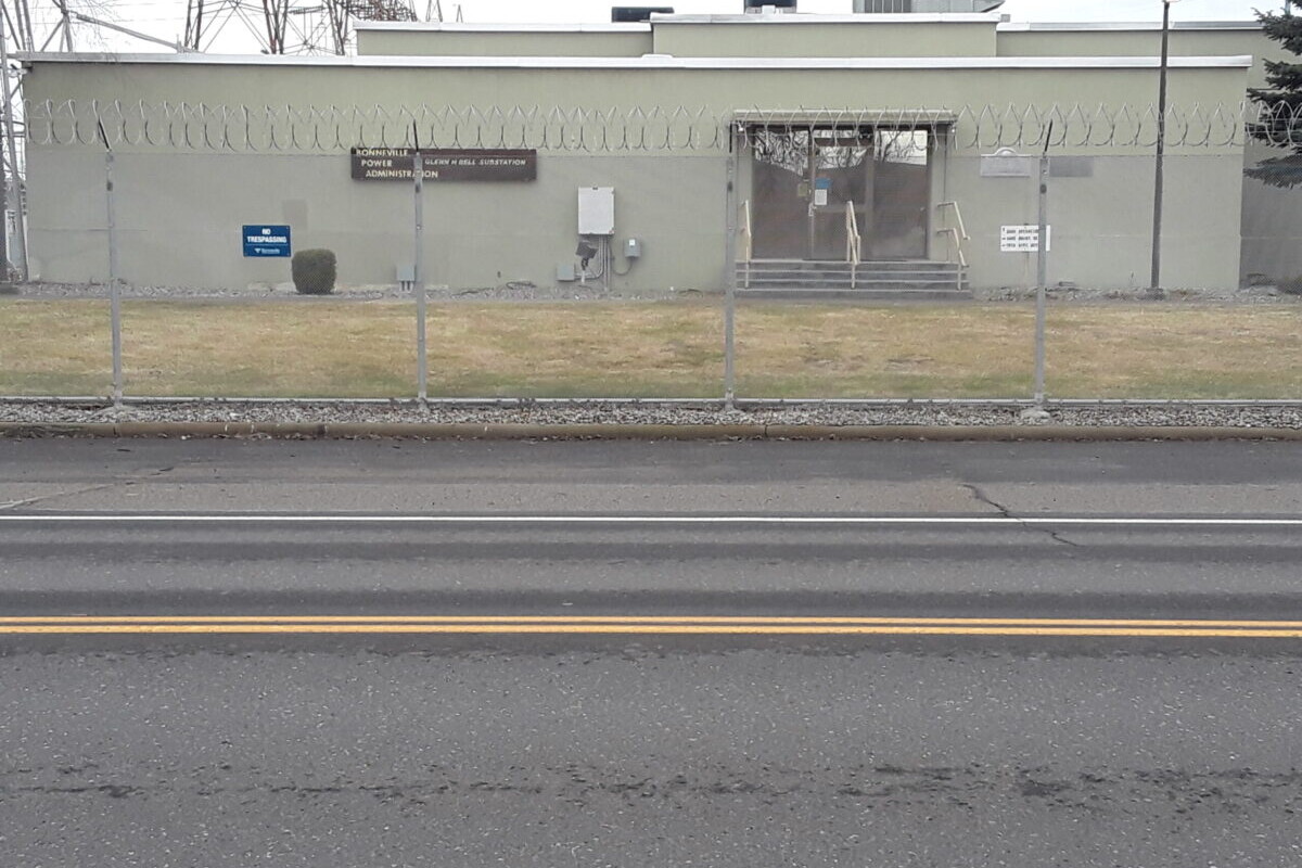 Street view of building behind chain-linked fence.