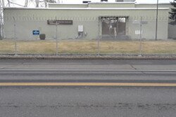 Street view of building behind chain-linked fence.