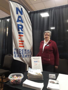 Lady standing next to feather banner that says NARFE