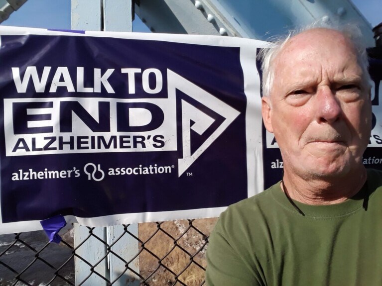 Man in front of sign for Walk to End Alzheimer's.