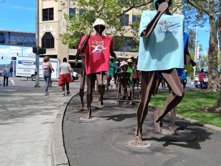 Iron statues running while wearing colored tee-shirts.