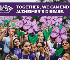 People walking holding lilac flower signs, with banner reading: Together, we can end Alzheimer's disease.