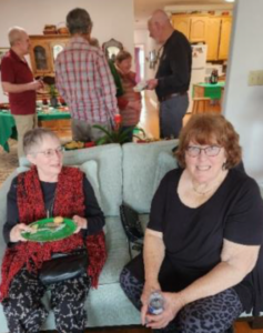 two women on sofa with group standing behind them