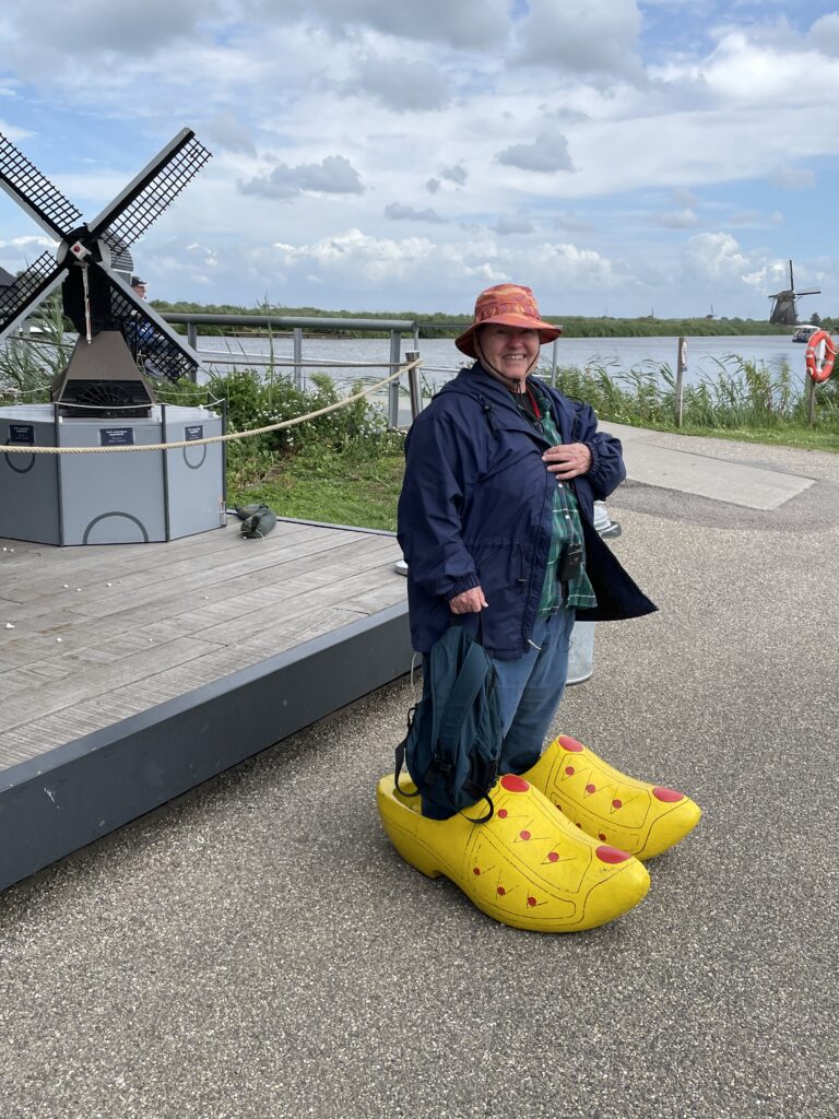 woman standing in wooden shoes with windmill in background