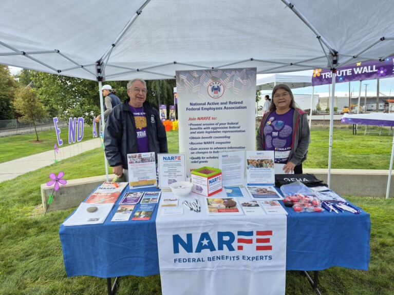 people standing behind NARFE table at event