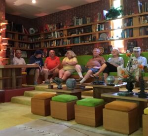 Seven members seated in front of a ceiling-to-floor bookcase