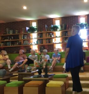 Seven people sitting in the library listening to the presenter standing