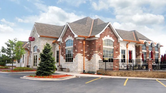 side view of red and white brick building with wrought-iron fence around patio on right