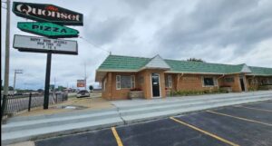 restaurant sign on left and brick building with green roof