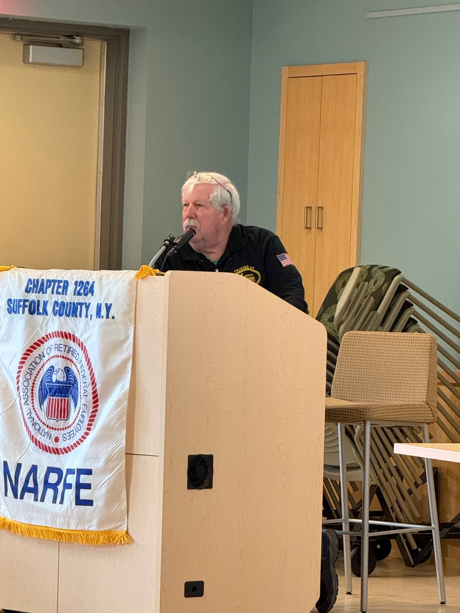 Man standing behind a podium speaking to the Chapter members.