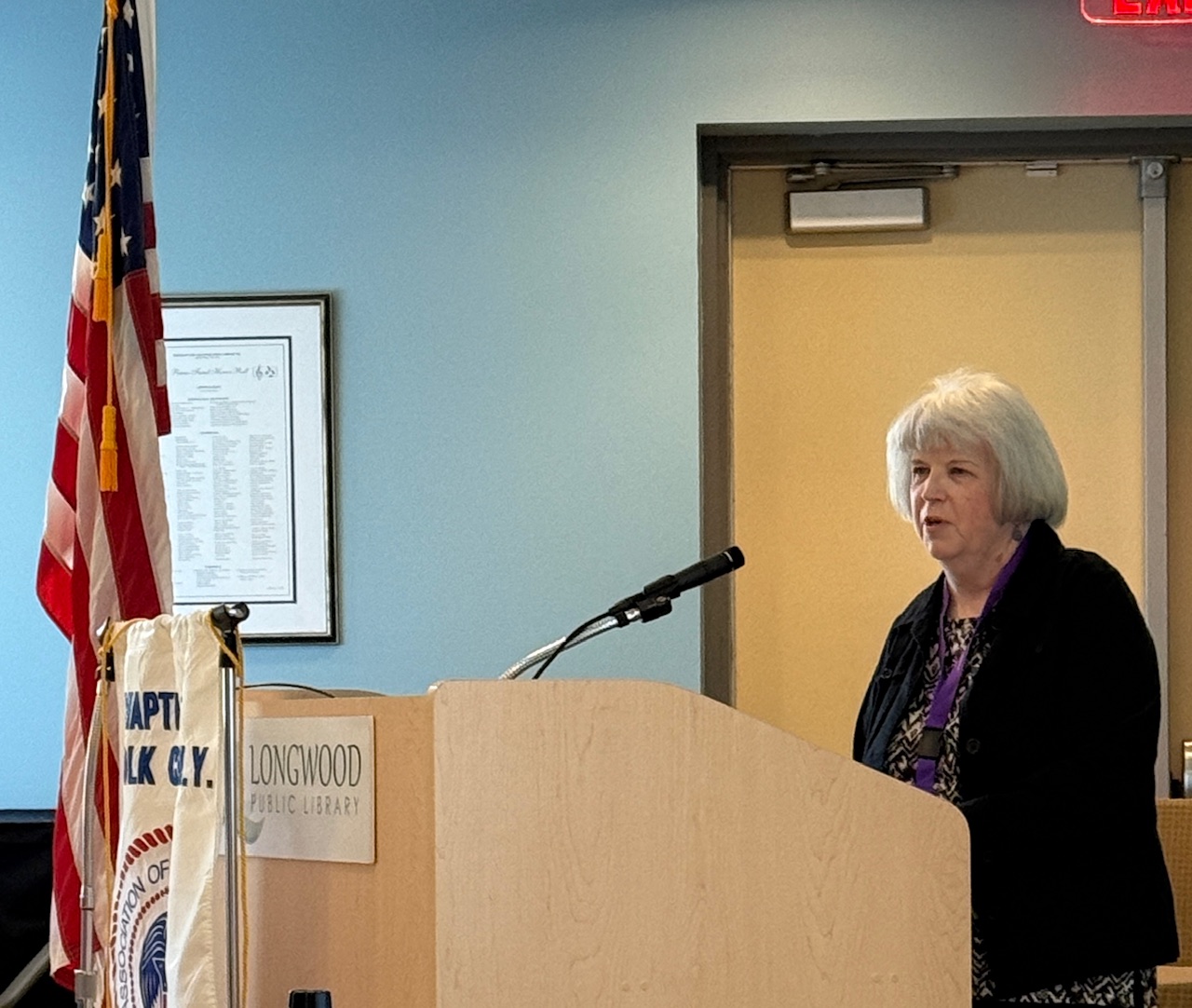 Women standing behind podium next to American Flag.