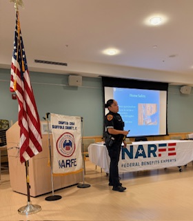 Female uniformed police officer standing near flag in front of a podium.