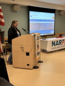 women standing behind podium giving presentation.
