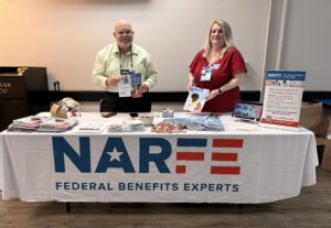 Two people standing behind a table holding NARFE information