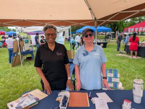 2 women under canopy at a table containing NARFE materials