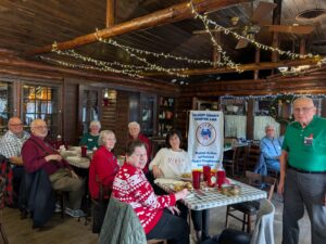 Multiple people gathered around 2 tables with chapter banner