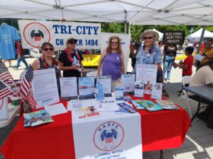 Several members of the NARFE Chapter 1494 stand around their table with handouts.