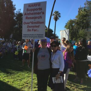 Two people posing with NARFE banner at Alzheimer's walk