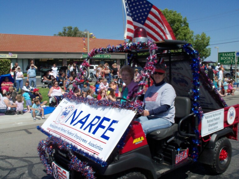 Two ladies in red, white and blue decorated farm vehicle