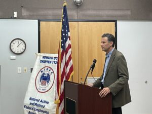 man at podium by U.S. flag and Chapter 1734 banner