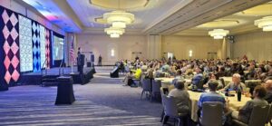 speaker on stage before a hotel conference room of NARFE members