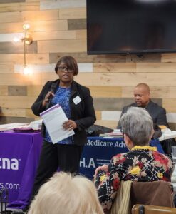 woman speaking on microphone at health care open season lunch