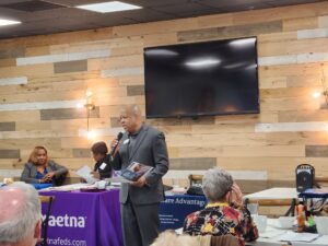 man with microphone speaking at open season lunch