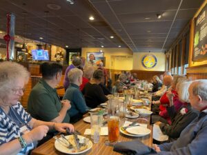 Restaurant dining room full of men and women after lunch.