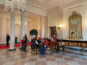 “The President’s Own” Marine musicians playing in a White House Foyer with chandeliers, marble floors and an engraved harpsichord.