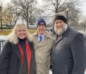 Three people outside the White House perimeter in winter.