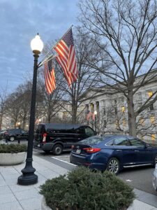 Lamppost by parking area on the White House grounds at dusk with 3 American flags.