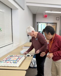 Large chocolate sheet cake decorated with NARFE Chapter 1734 logo on long table being served.