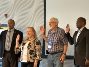 4 people with their right hands raised in front of a conference room