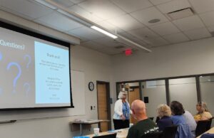 woman speaking by projected slide in classroom of adults