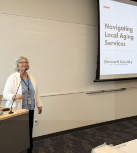 Woman at podium microphone beside slide projection