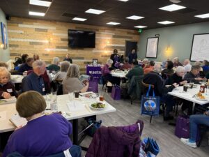 Woman speaking to a room of people at tables