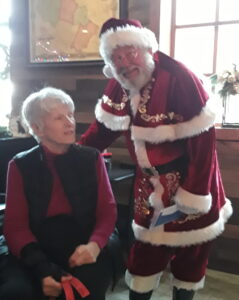 woman seated next to man in Santa Claus suit