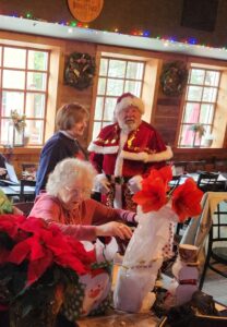 2 woman and a man in a Santa suit in restaurant