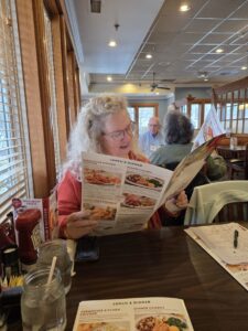Woman reading restaurant menu with other patrons in the background