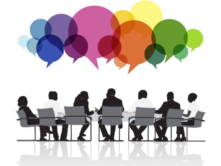 Image of seven people seated and talking in a meeting