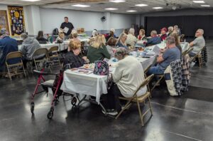 Chapter meeting with attendees sitting around tables listening to guest speaker, about health care information.