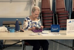 Member busy fielding information, sign-in sheet, and 50/50 Raffle Tickets