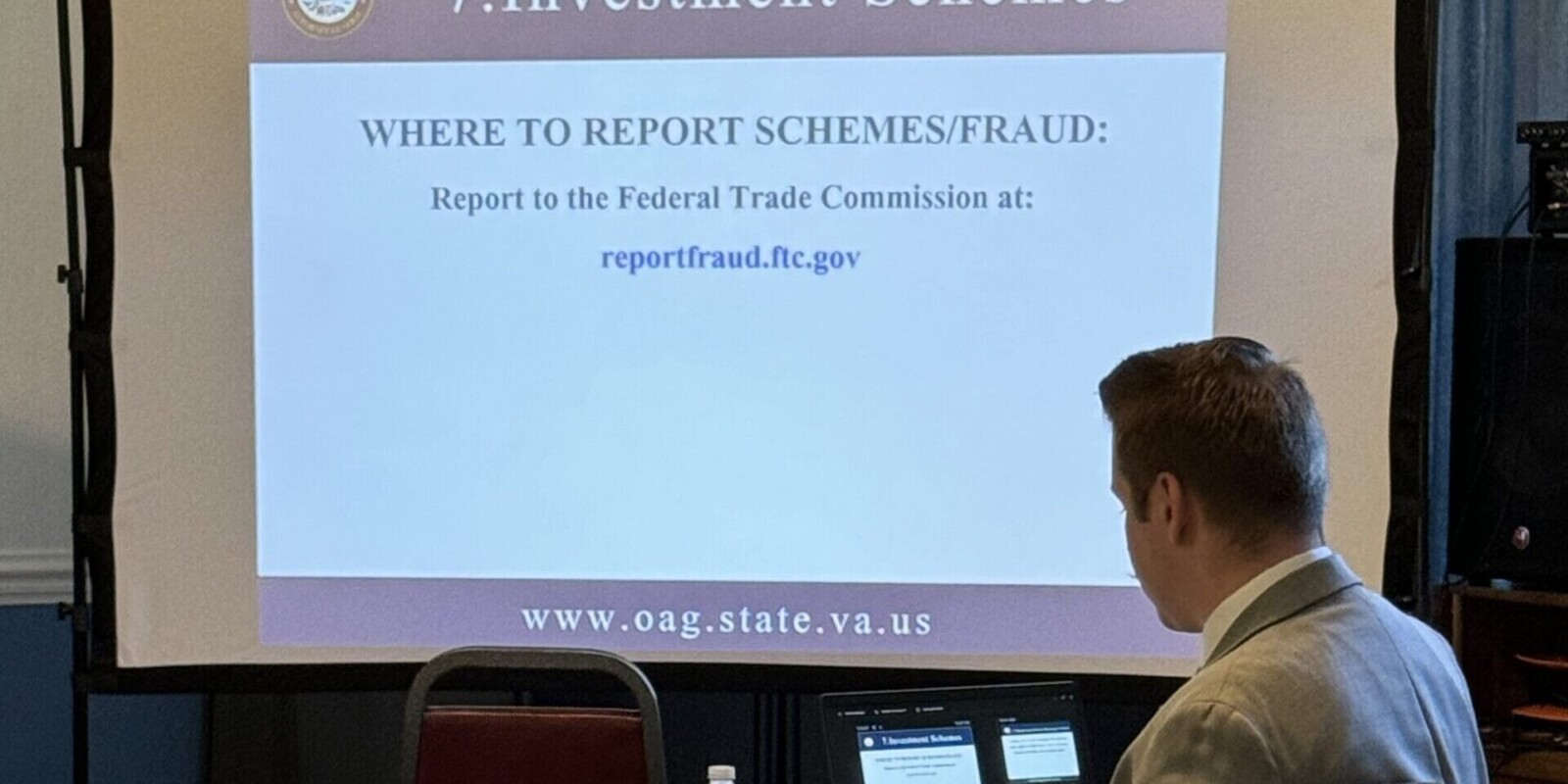 Speaker sitting at laptop with slide projected talking about Investment Schemes