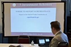 Speaker sitting at laptop with slide projected talking about Investment Schemes