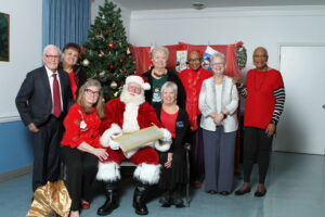 Group gathered around Santa in front of a Christmas Tree